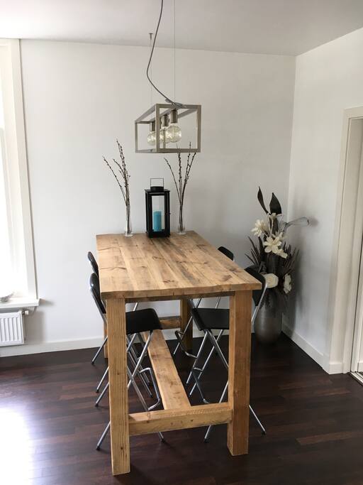 A modern lamp hangs above the bar table made from massive wood which, together with the four bar stools, is perfect for having dinner or working behind a laptop