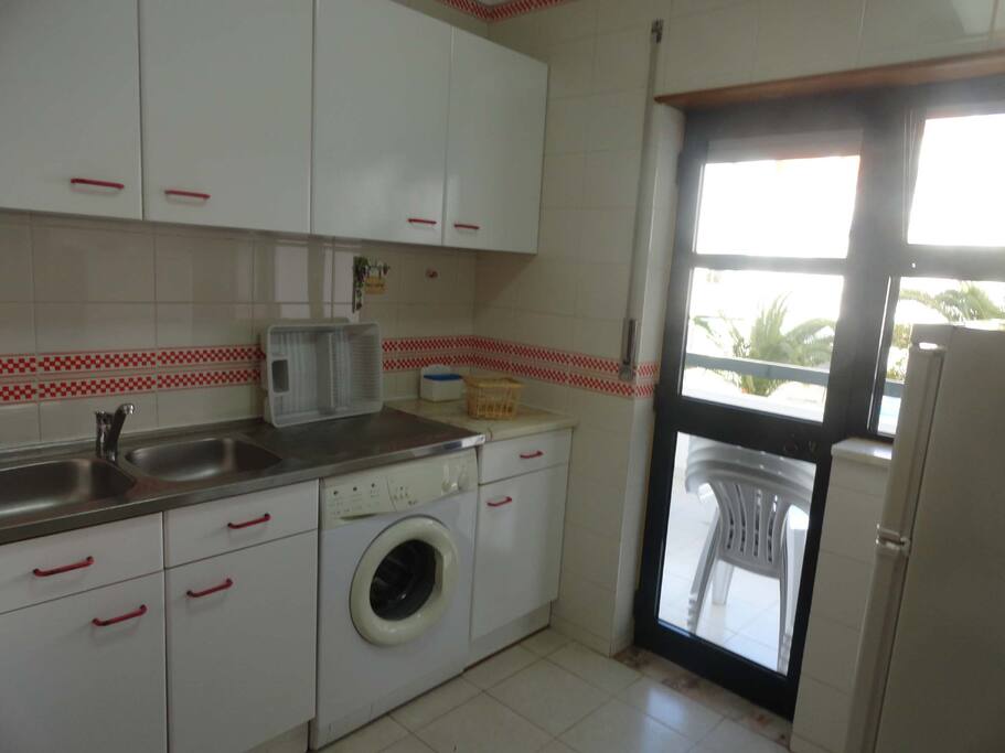 cozinha equipada voltada para varanda com mesa e cadeiras