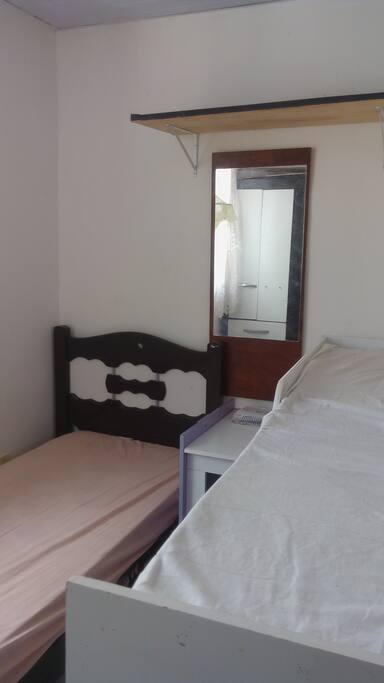 quarto com 2 camas e espelho com guarda roupas e cabides