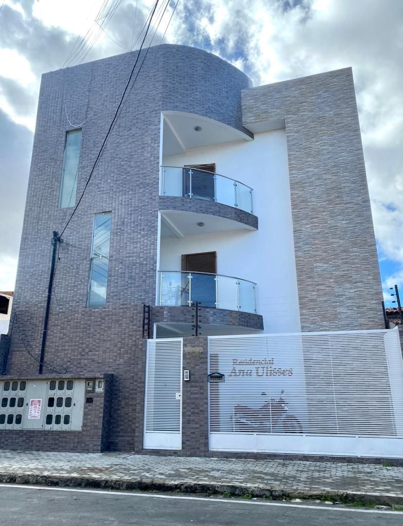 The modern building features a unique architectural design with a combination of light and dark brick exteriors. Balconies are visible on the upper levels, surrounded by glass railings. A gated entrance provides privacy, while a mural of a bicycle adds a charming touch to the facade.