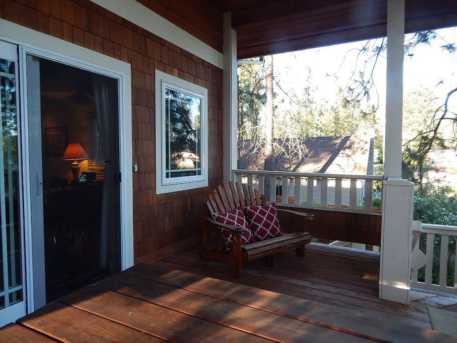 Large covered front deck of Guesthouse with BBQ, picnic table, and comfortable views of lake.