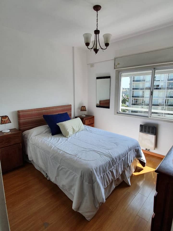 ห้องนอนหลักพร้อมเตียงคู่ทีวีพร้อม Chromecast หน้าต่างด้านนอกเครื่องปรับอากาศและเตาไฟ 