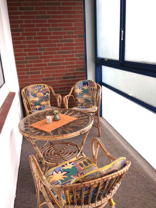 Verglaster Balkon mit Esstisch und zu öffnenden Fenstern