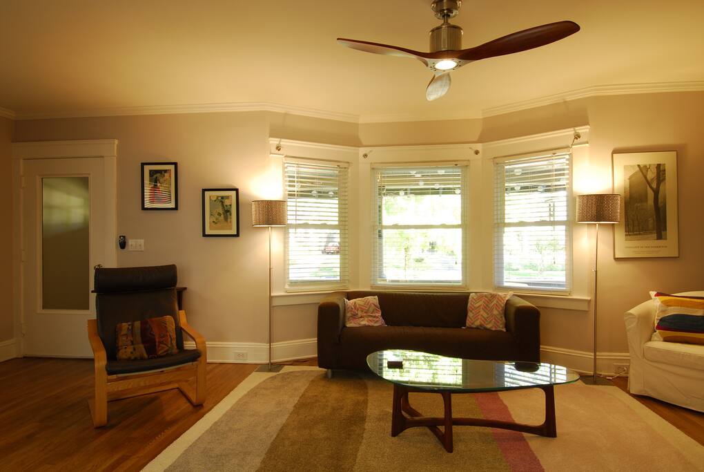 Living room with bay windows overlooking a tree-lined street