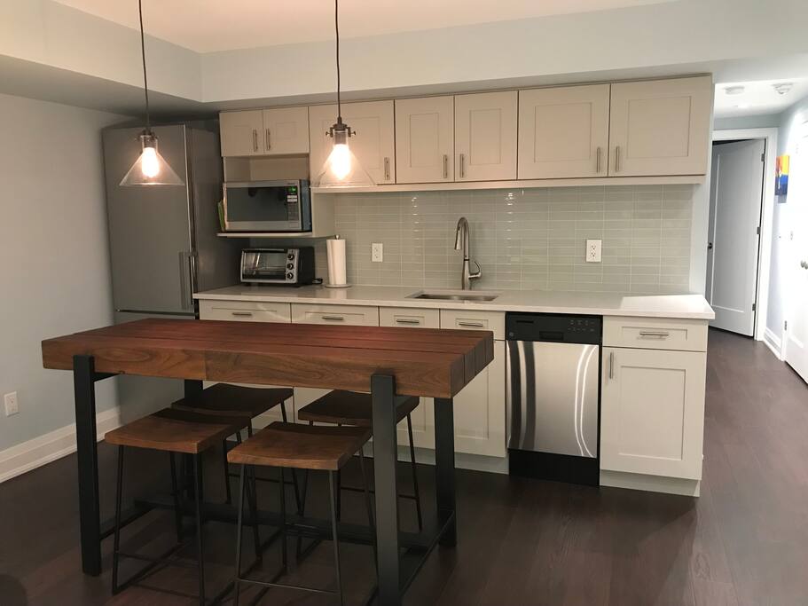Breakfast Bar and Fully Equipped Kitchen with refrigerator, microwave, toaster-oven, dishwasher, sink and hotplate.