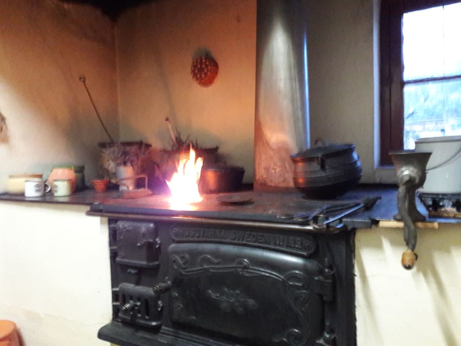 Wooden stove in the kitchen with fire burning in cold winter nights