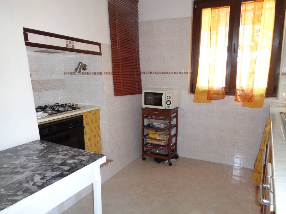 Angolo cottura con tavolo di appoggio,e credenza a muro e finestra