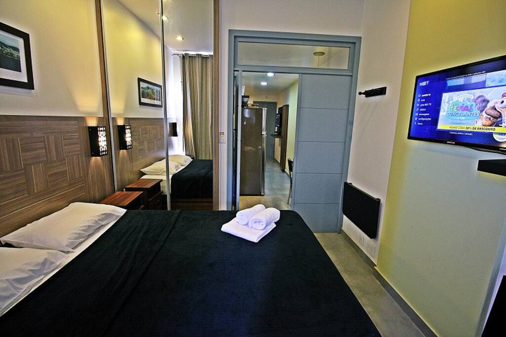 Quarto com cama de casal, asr condicionado, TV LCD e armário.