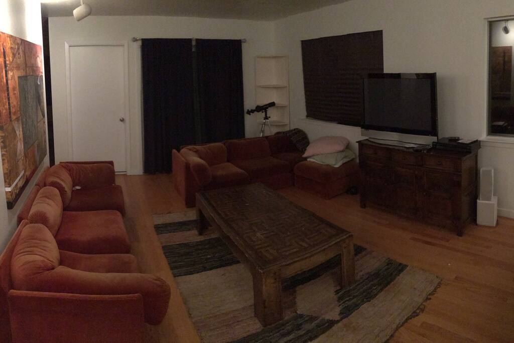 Spacious living room space with TV, large couch space, a coffee table, and much natural lighting during the day.