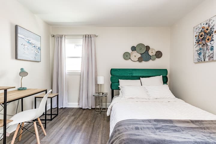 Entspanne dich in unserem einladenden Schlafzimmer mit einem komfortablen Queensize-Bett, einem Nachttisch mit einer Lampe und einem speziellen Tisch und Stuhl für deinen Arbeitsplatz.