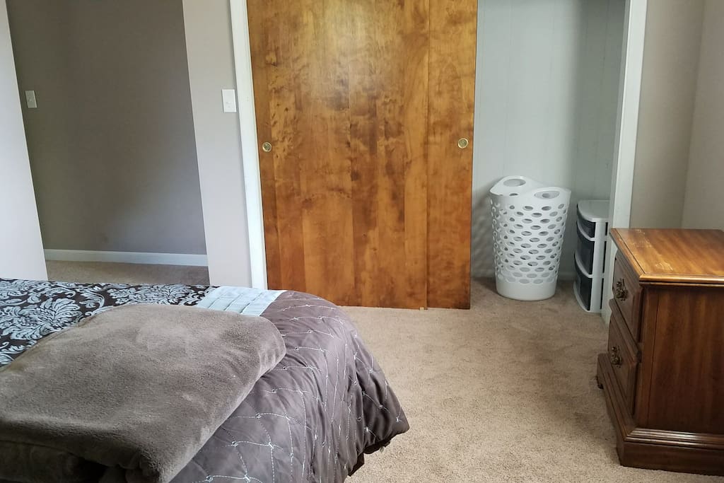 Full size closet with hangers, hamper, and extra linens.