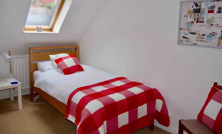 Прв голем единечен кревет во втората спална соба со ноќна масичка и индивидуално светло за читање.