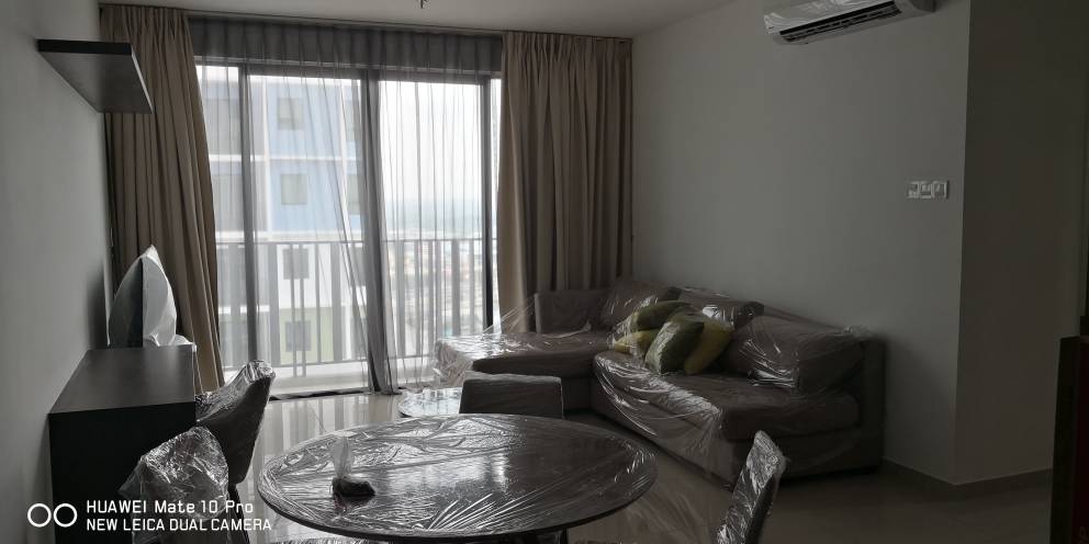 A modern living area is captured with a large window allowing natural light to enter. A round dining table is present alongside a sofa with cushions. Light-colored curtains frame the window, while a flat-screen TV is mounted on the wall.