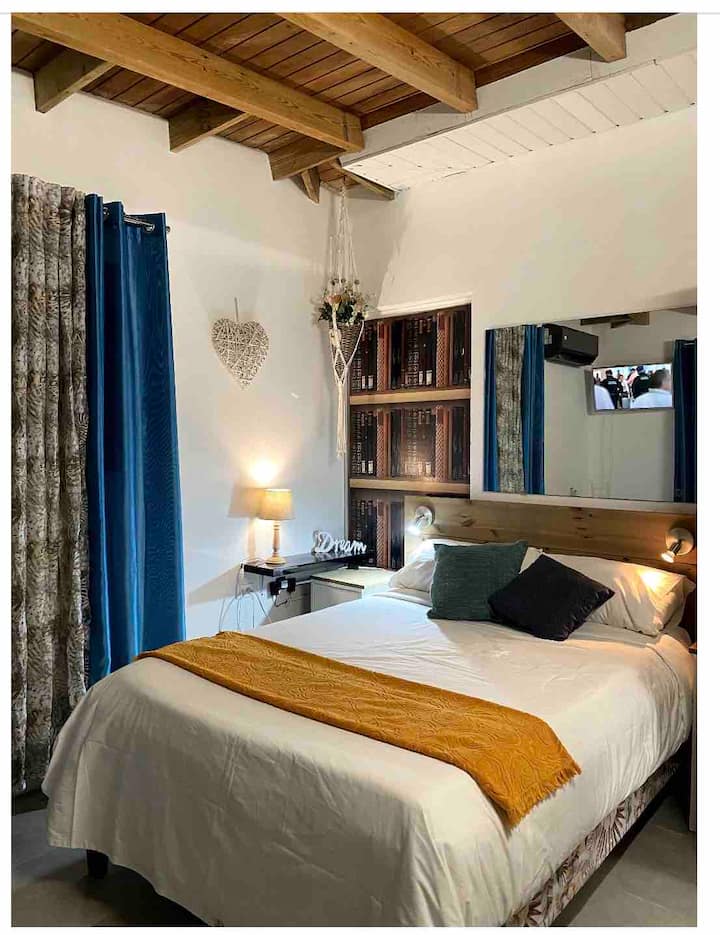 Terceiro quarto com cama queen e cozinha pequena com geladeira, TV  e banheiro privativo.
