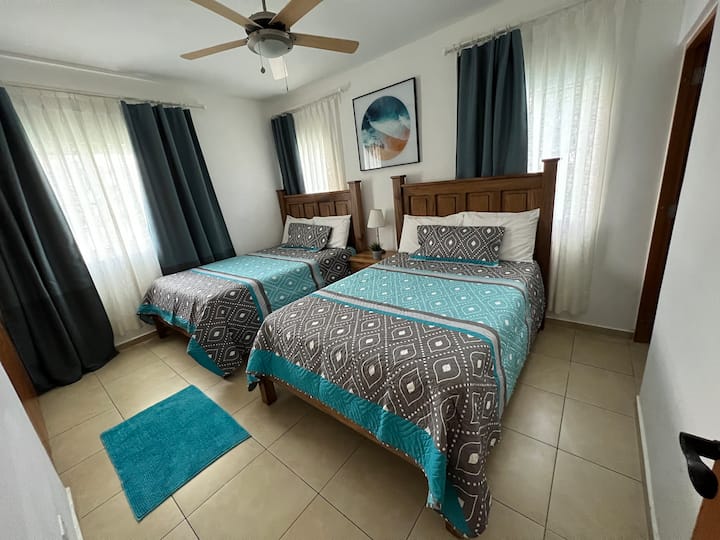 Rum med två fullständiga sängar och dess badrum.