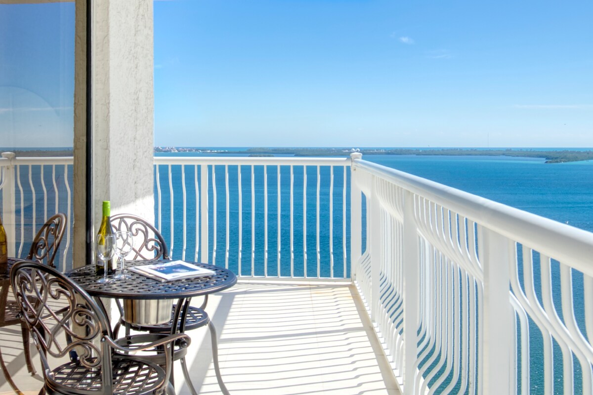 A private balcony features a cast-iron table and two chairs, overlooking stunning views of the Atlantic Ocean. The space is bathed in natural light, with a spacious feel that invites relaxation and enjoyment of the coastal scenery.