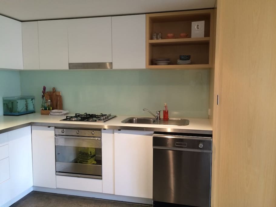 Open plan kitchen with fully integrated washing machine, fridge and oven/stove.