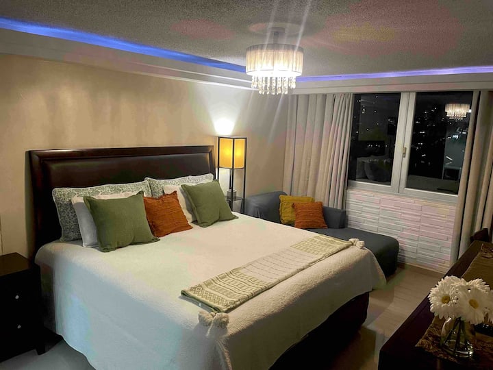 Dormitorio principal con cama tamaño king y sofá pequeño