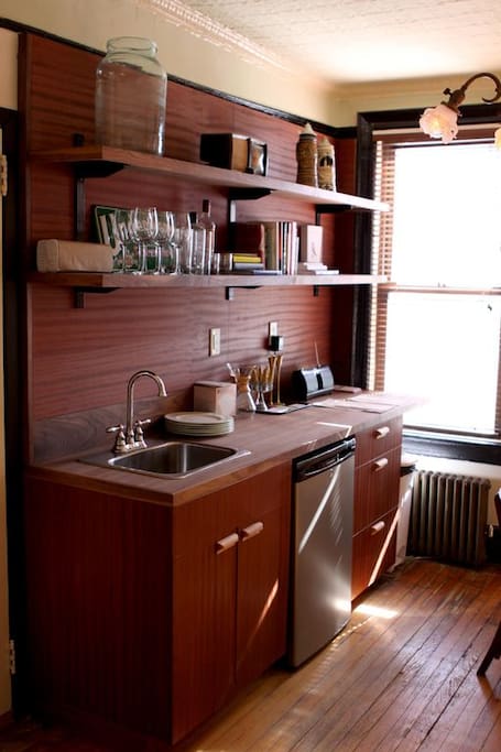 Cozy kitchenette with dining table, sink, small fridge with Chemex coffee maker.