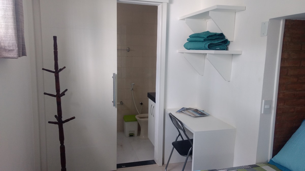 ห้องนอนคู่พร้อมเตียงและผ้าปูที่นอนในอ่างอาบน้ำพัดลมเพดานและโต๊ะทำงาน