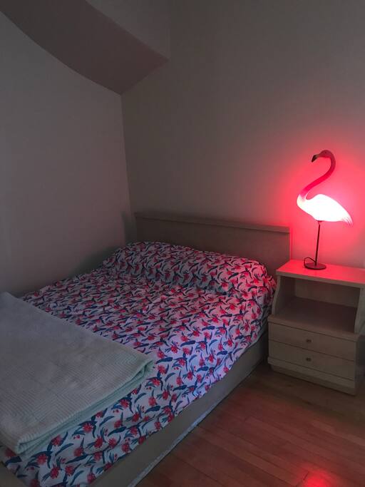 Full-size bed, nightstand (there is a hairdryer for you inside the drawer), and a soon-to-be world famous flamingo lamp!
