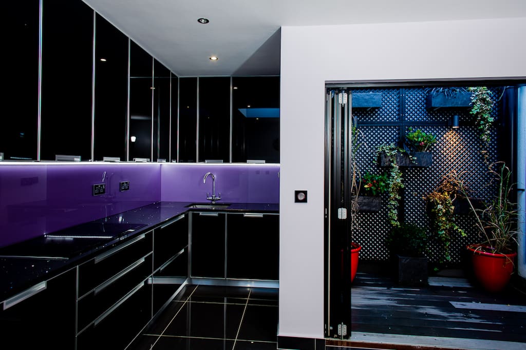 Modern Italian glass kitchen designed by Scavolini - Double doors open onto planted patio garden