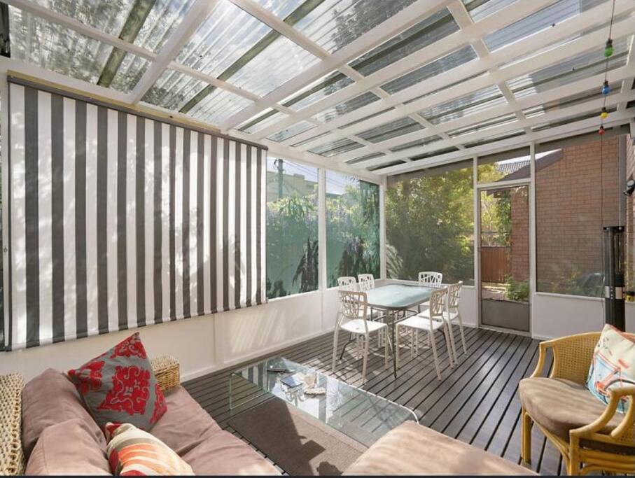 Sunny outdoor covered patio with chaise lounge, outdoor table setting for 6, outdoor heater and BBQ.