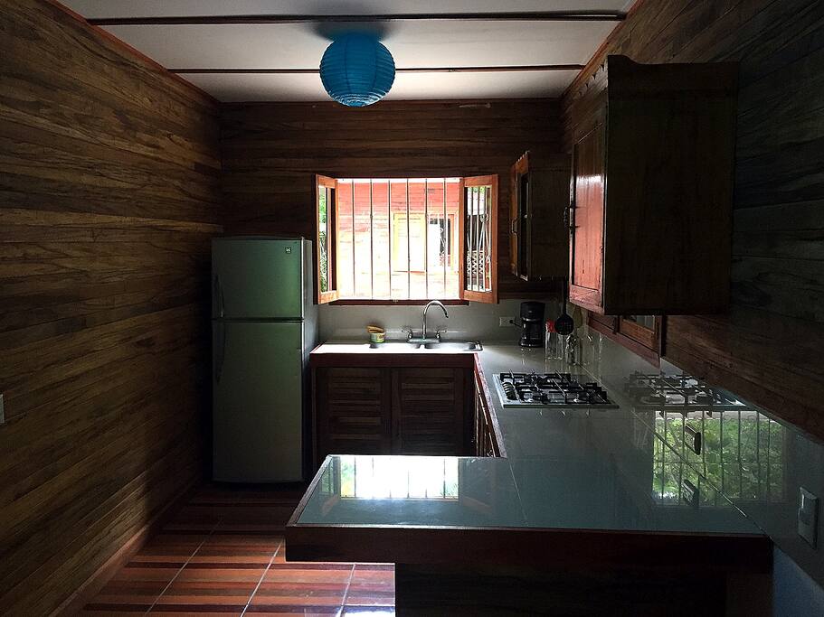 Cocina con refrigeradora y utensilios básicos para cocinar.