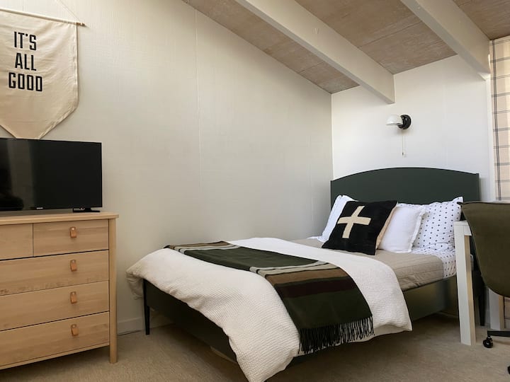 Upstairs bedroom with two twin beds, desk and smart tv.