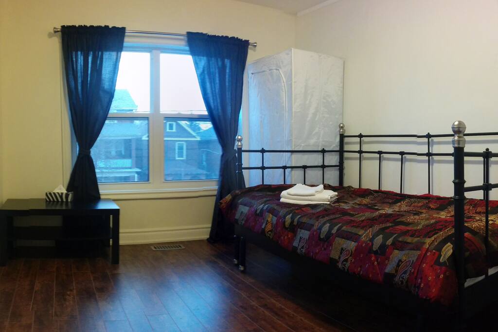 the room with bed, closet, coffee table, full length mirror, towels, garbage bin, notepad and pen