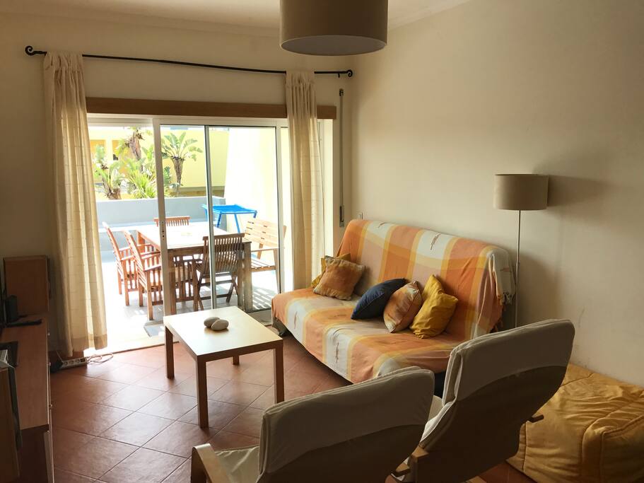 Vista geral da sala de estar com acesso à varanda e vista para a piscina, mini golf e parque infantil
