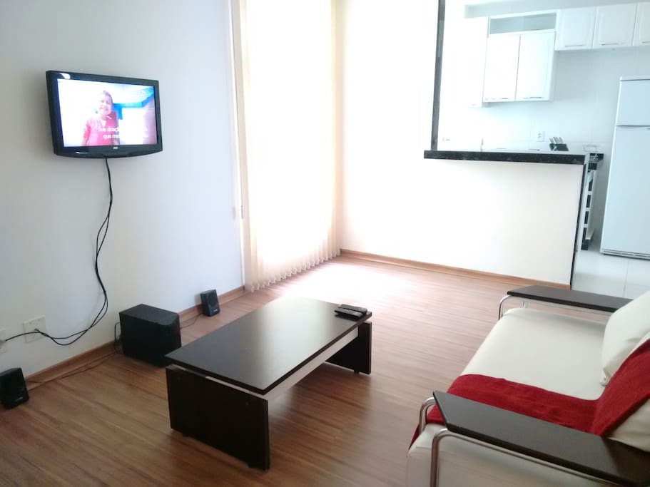 Sala com TV, mesa de centro, sofá e aparelho de som