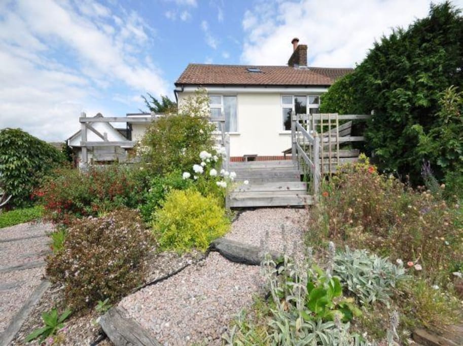 Front of the house with sunny decking and seating.