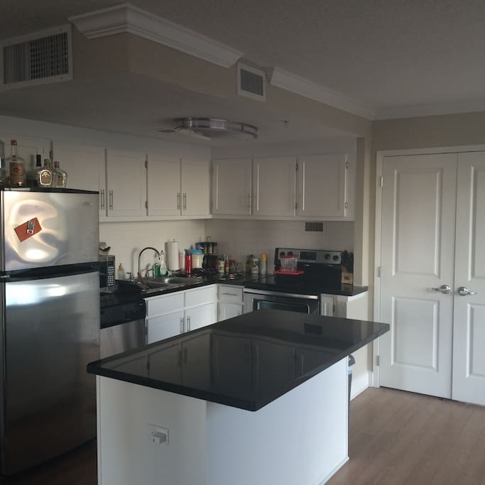 Kitchen with stainless steel fridge and oven/stove, and microwave. Granite counters with a granite island