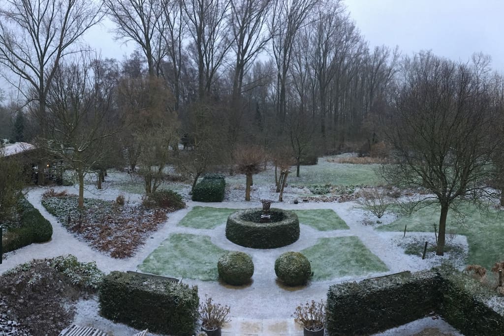 Achtergevel ziet uit op tuin bij lichte sneeuwval
