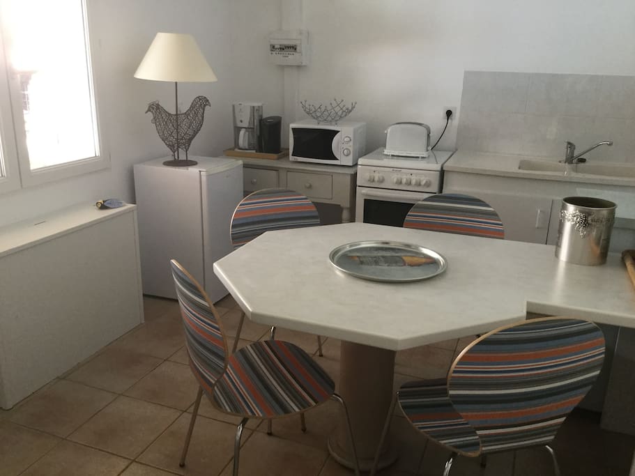 Cuisine avec 2 réfrigérateurs dont 1 avec compartiment freezer indépendant, bouilloire, cafetière, micro-ondes, cuisinière électrique, fenêtre ouvrant sur pergola et piscine.