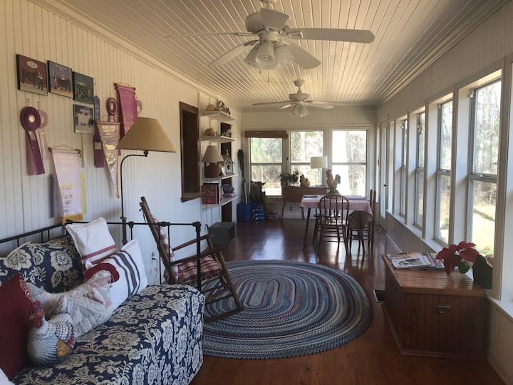 Sunroom with windows throughout offers stunning views of the forested backyard and 4 acre private pond behind the cottage.