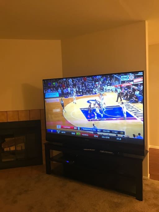 Large TV next to wood burning fireplace.