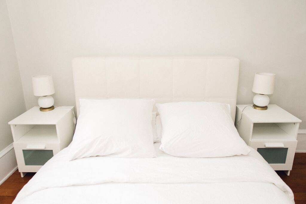 Bed has white linen duvet cover and pillow shams.