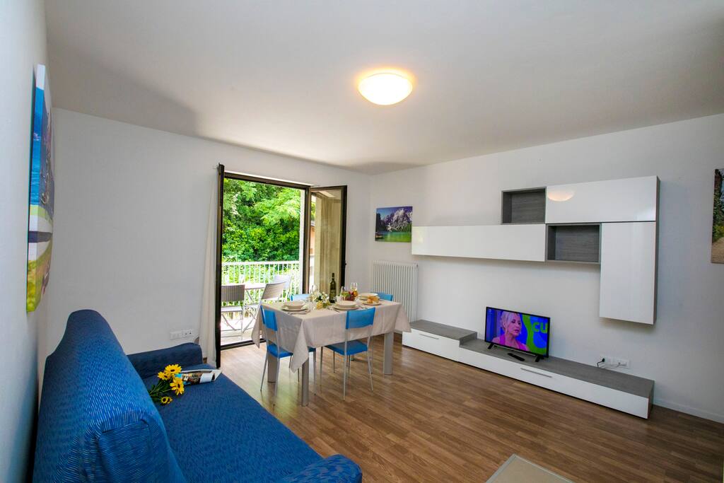 The bright living room with sleeping sofa, dining set and entranc to the terrace