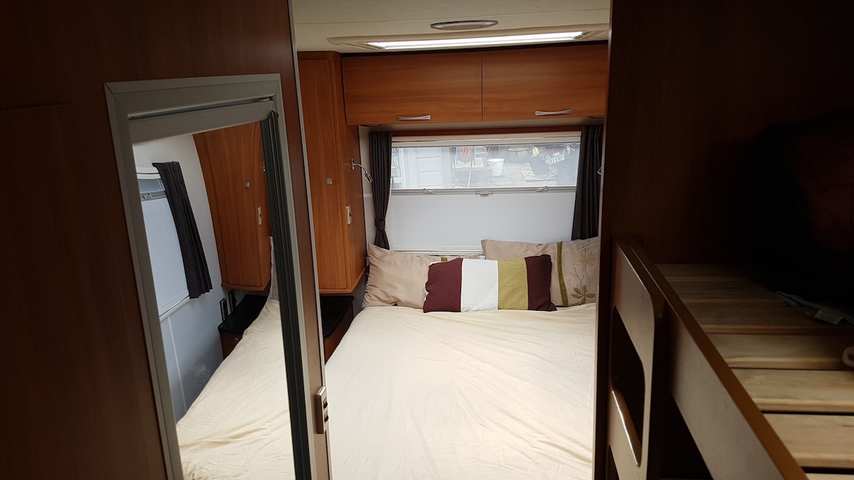 מיטה זוגית עם חלונות בכל מקום וטלוויזיה