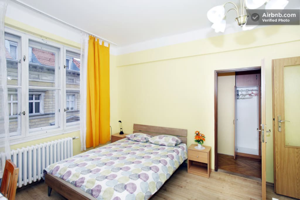 The second bedroom contains a double bed, a single bed (not shown), table with chairs, and a walk-in closet with a wardrobe
