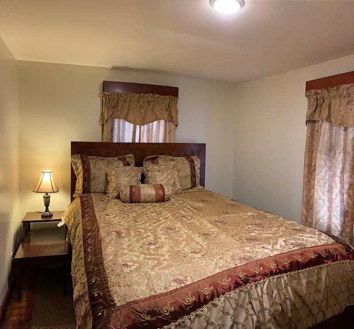 غرفة نوم كوين مع تلفزيون بشاشة مسطحة مثبتة على الحائط وخزانة وطاولة وحدة تحكم صغيرة. 