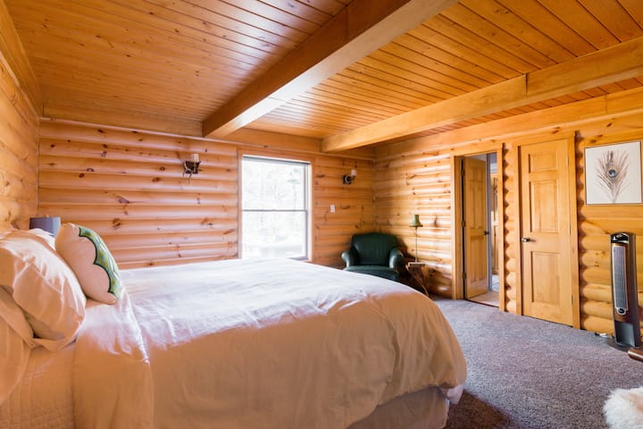 Downstairs king bedroom, furnished with new linens and bed.  All beds and bedding in the house are new.  Exposed logs create a rustic yet modern vibe.  