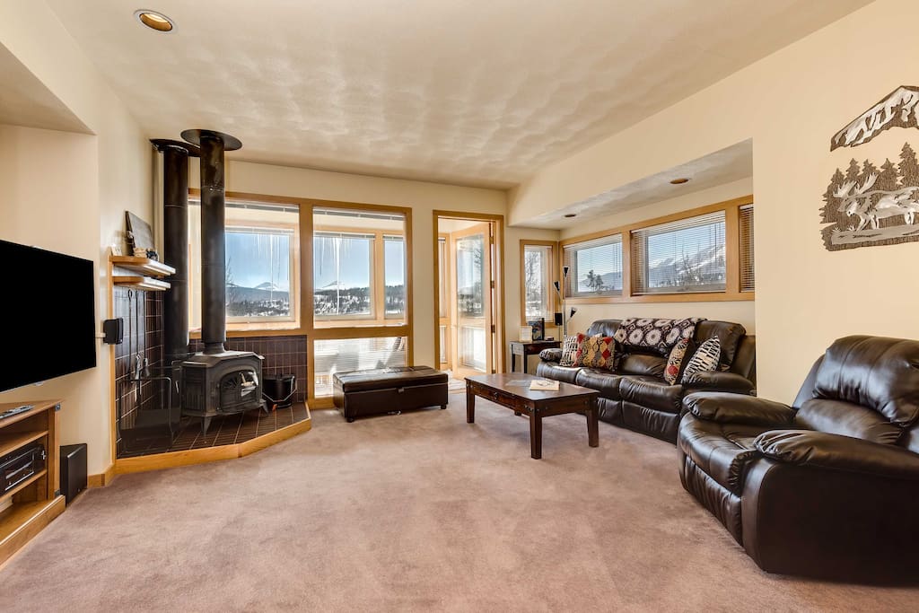 Living room with reclining couches, smart tv, wood stove and twin ottoman