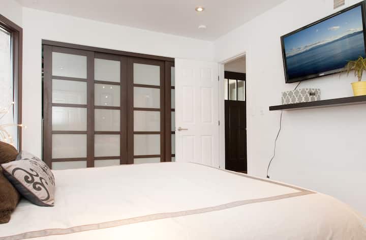 חדר שינה ראשי עם מיטת קווין סייז וחדר רחצה צמוד.