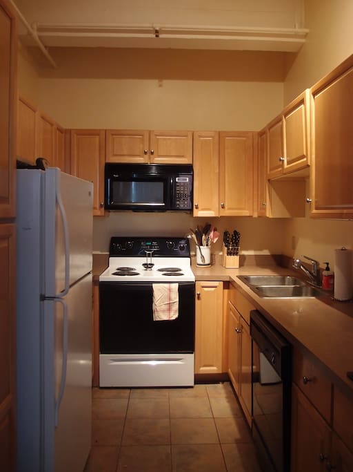 Kitchen with dishwasher, stove, microwave, fridge, and basic cooking/dining essentials.
