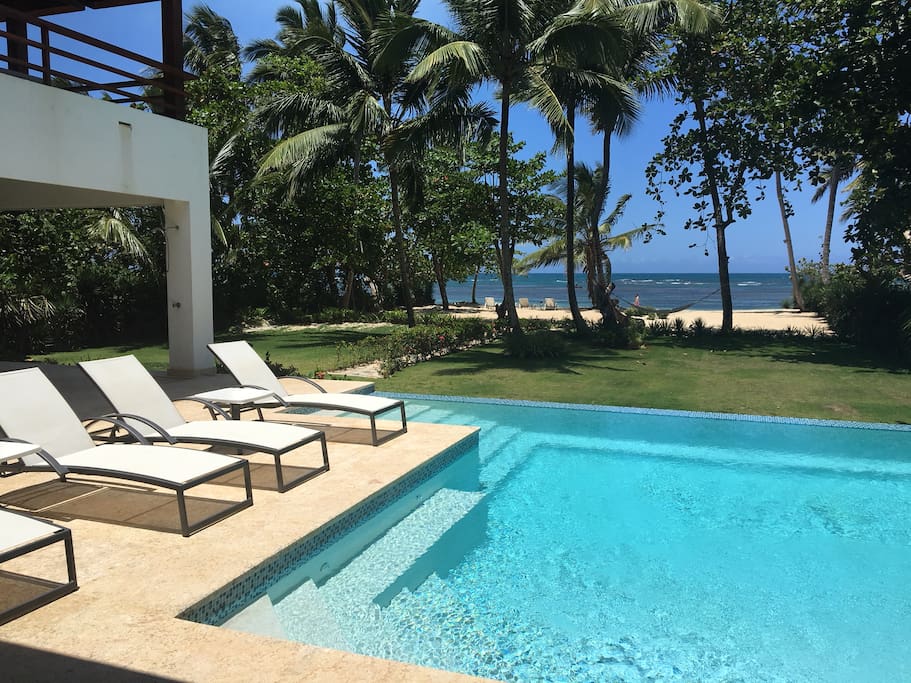 Infinity pool with built in seating looks out on private yard and beach.