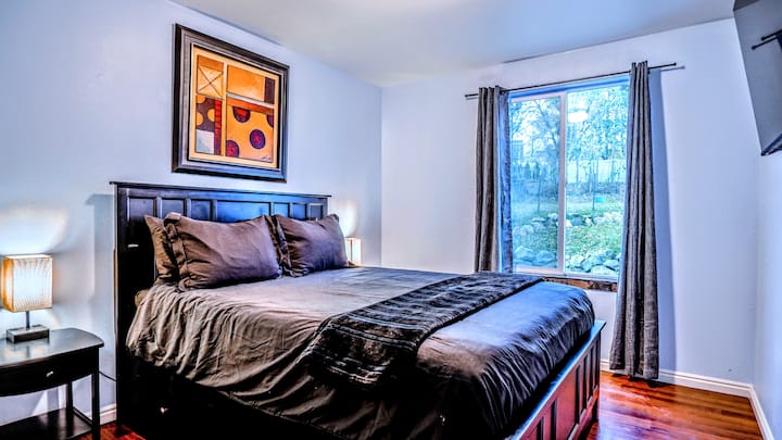 The second bedroom with queen bed, large 4K smart TV, and sliding window