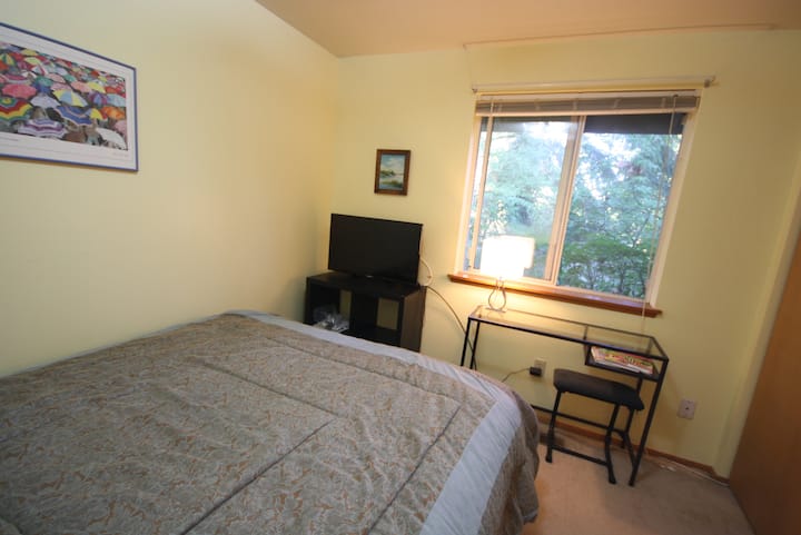dormitorio de invitados con cama tamaño queen y televisor de 32 pulgadas
